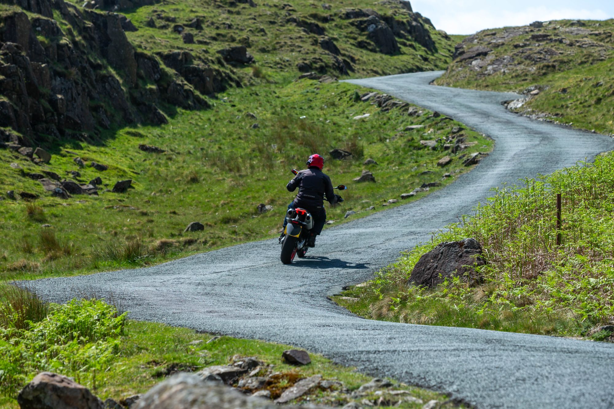 Motorcyclist riding a winding mountain pass in the Lake District